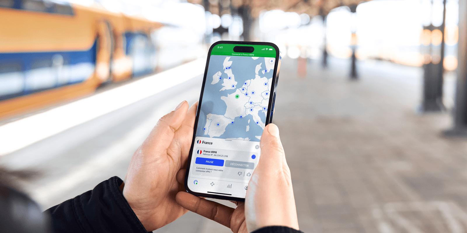 iPhone affichant l'application NordVPN connectée à un serveur en France, tenu sur un quai de gare
